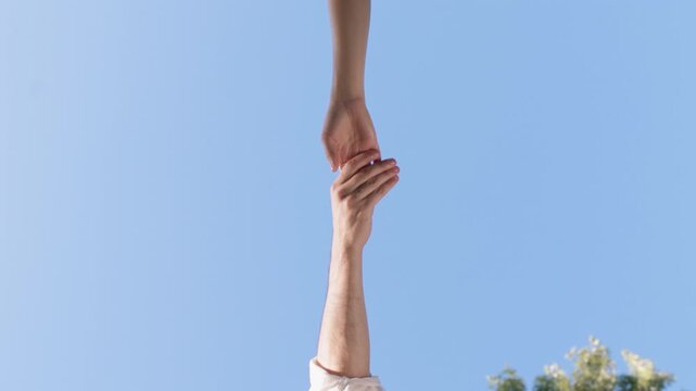 Two people releasing hands against blue sky after supportive touch. Support, farewell, trust, connection, hope, independence and moving forward
