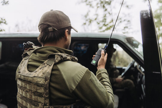 Ukrainian soldier communicating by radio near military vehicle