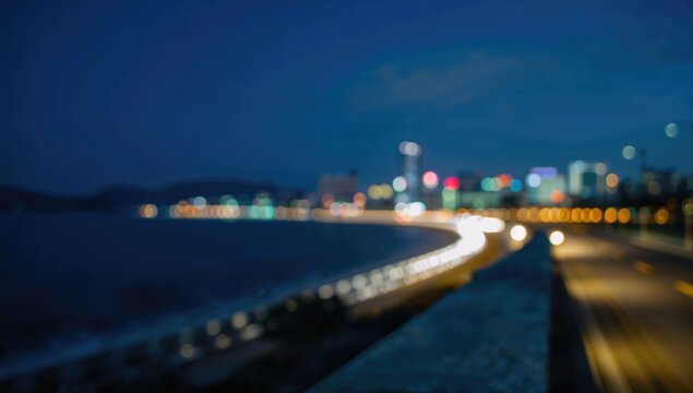 City Lights Shimmering Along a Coastal Road at Night in Blurred View