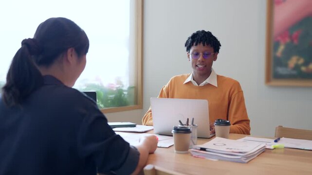 Young African American businessman talking and discussing project with Asian colleague in modern office