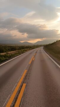 Empty road in Norwegian mountains at sunrise, vertical travel landscape.