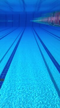Empty indoor swimming pool lane underwater view with blue reflections.