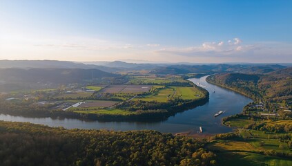 Fototapeta premium Aerial View of a Serpentine River Meandering Through Lush Green Fields Under Clear Blue Skies