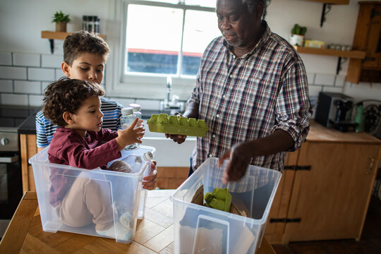 Grandparent and children sorting recycling in home kitchen