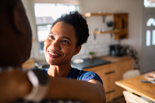 Smiling woman embracing partner in home kitchen