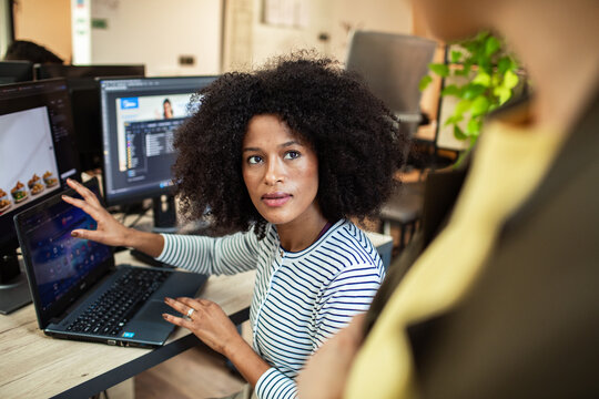 Professional explaining code to colleague in modern office