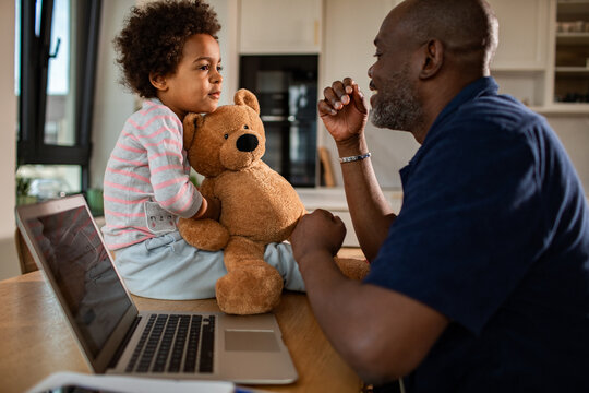Parent and child playing with teddy bear at home office