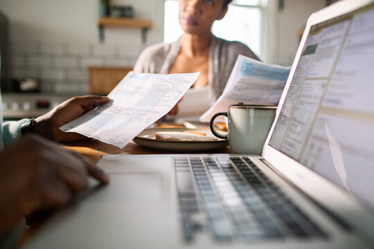 Couple reviewing household bills on laptop at kitchen table