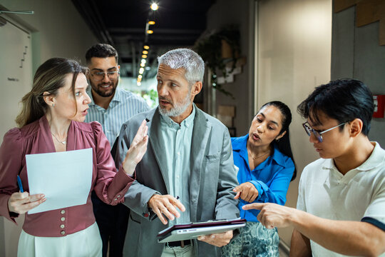 Diverse coworkers discussing project in office hallway