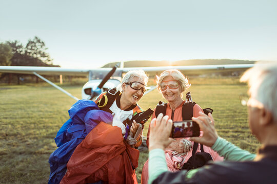 Senior women skydivers smiling at rural airfield