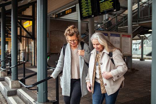 Two mature women with backpacks walking at train station