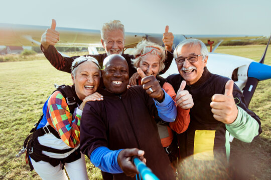 Happy senior skydivers taking selfie at airfield