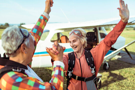 Senior women celebrating after skydiving at airfield