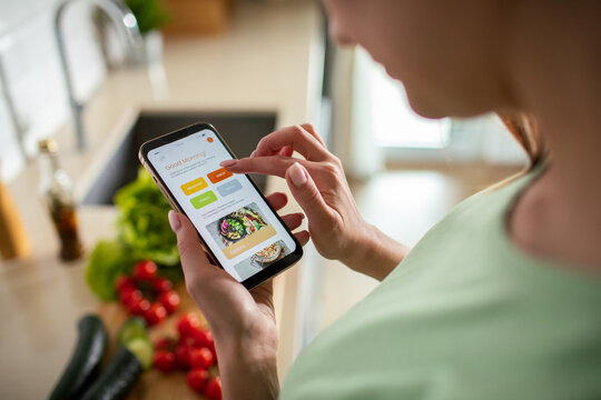 Young woman using meal planning app in home kitchen