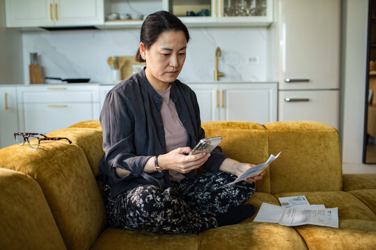 Woman paying household bills on smartphone at home