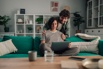 Happy couple shopping online together from home using a laptop and credit card for e commerce