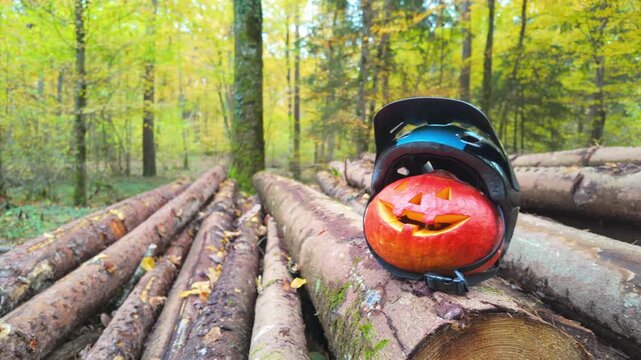 Carved Halloween pumpkin wearing a helmet in the forest