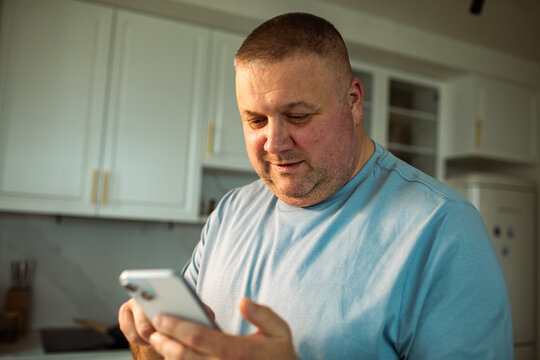Middle-aged man using smartphone in home kitchen