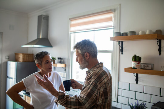 Mature couple talking over coffee in kitchen