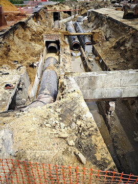 Utility crews install underground pipes during roadwork construction