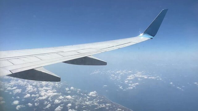 View from the airplane window. Beautiful cloudscape with blue sky. Wonderful panorama above white clouds as seen through window of an plane. Traveling by air concept. 
