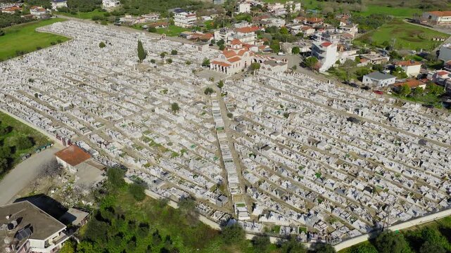 Slow panoramic drone pan of Pyrgos cemetery, Ilia, Greece. Rows of graves and monuments under clear sunny sky