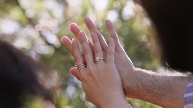 Close-up of a couple admiring an engagement ring on a woman's hand after a marriage proposal. Romantic outdoor moment in natural sunlight symbolizing love, commitment, future together and a new