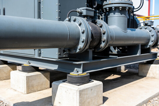 Industrial pipe system with vibration dampeners on concrete foundation