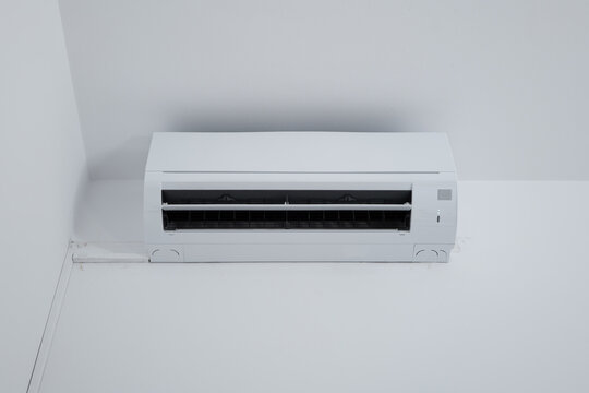 Straight-on shot of a modern white ductless split air conditioner unit with its air flap open.