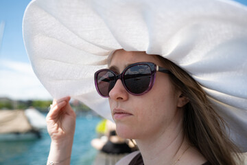 Profile portrait of a woman in a large white floppy sun hat and sunglasses, shallow depth of field © Octavian