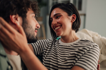 Obraz premium Cheerful couple embracing, touching face, expressing love and trust in a cozy home setting, enjoying their relationship