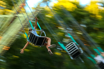 Caucasian Person on Carousel Swing Ride with Motion Blur in Summer Amusement Park © Екатерина Переславце