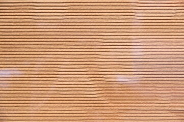 Obraz premium Kraft corrugated cardboard texture behind glass with horizontal ribbed lines and soft light reflections on the surface