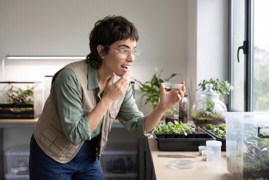 Woman scientist carefully observing small plants in a lab with excitement