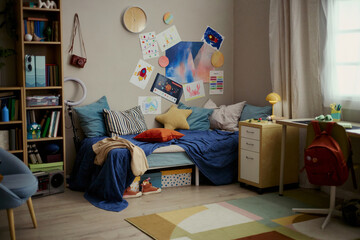 Wide shot of teenager bedroom displaying study desk, bed, backpack, creative drawings and school supplies, suggesting student routine and youth lifestyle. Useful for education or parenting campaigns © DragonImages