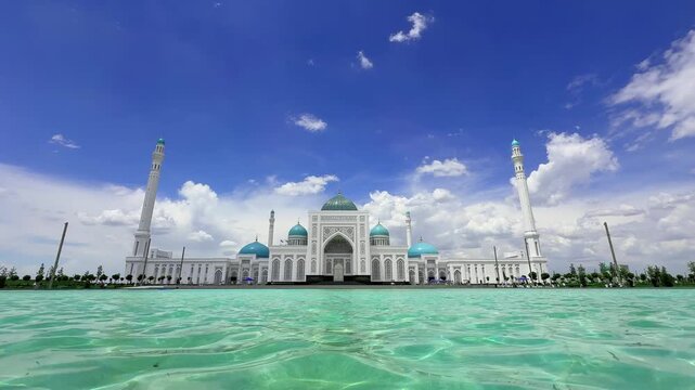 Wide view of the Imam Al-Bukhari Memorial Complex near Samarkand, Uzbekistan, featuring Islamic architecture, turquoise domes, elegant minarets and a reflecting pool under a bright blue sky with white