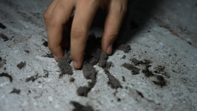 Close-up of fingers touching loose dirt on a rough white surface, Hand touching dirt on rough white surface