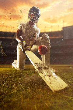 Cricket batter in defensive shot with red ball and flying dirt at sunset stadium. Concept of cricket competition, athletic precision, tournament marketing, sports branding and commercial campaigns.