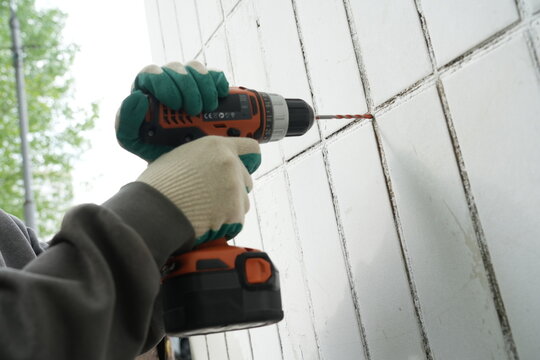 Drilling white tile building facade low angle close up