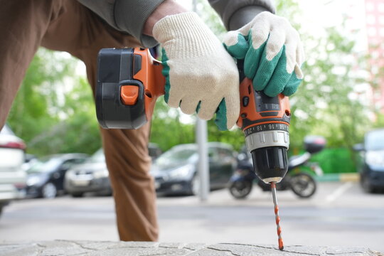 Close-up of worker drilling pavement tile in parking lot