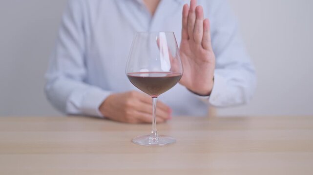 man making stop hand gesture to refuse a glass of Wine, Healthy man say no to alcohol drink, stop alcoholism and addiction concept. Responsible man reject a drink before driving and quit booze