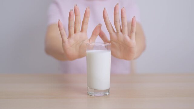 Lactose intolerance and Milk allergy. woman hand stop and refuse Milk, having abdominal cramps and pain when drink Cow Milk. Symptom stomach ache, Dairy intolerant, Nausea, Bloating, Gas and Diarrhea