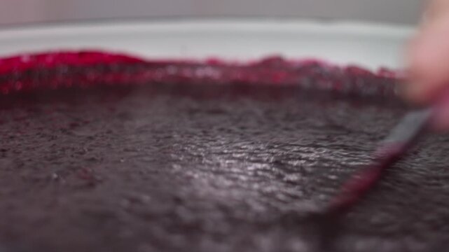 Close-up of a Chef Stirring Thick Berry Puree in a Glass Mixing Bowl