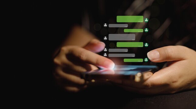 Hands using a smartphone for digital chat messaging and social media communication in low light conditions