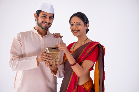Maharashtrian couple putting coin into money box