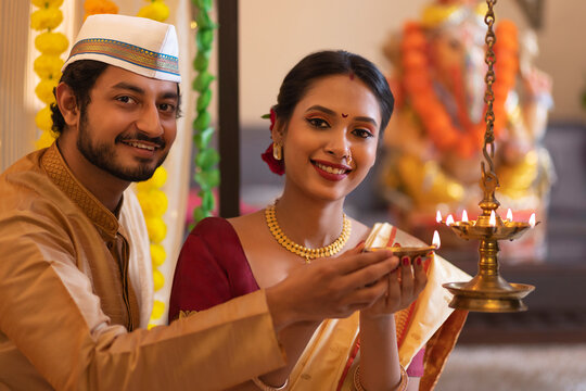 Maharashtrian couple lighting oil lamp on the occasion of Ganesh Chaturthi