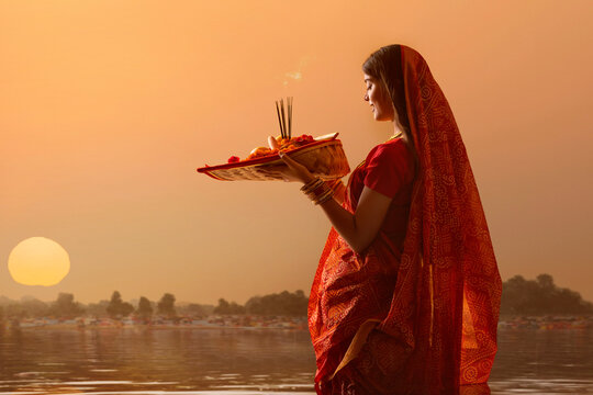 woman from Bihar offers prayers to the  sun  in the  early morning hours   during  Chhath Puja festival