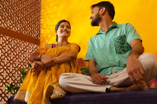 Gujrati couple talking while sitting on deewan in living room