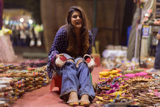 Gril selecting from two pairs of sandals in street shop