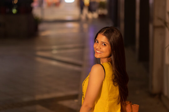 Woman looking back at camera with smile while walking on street